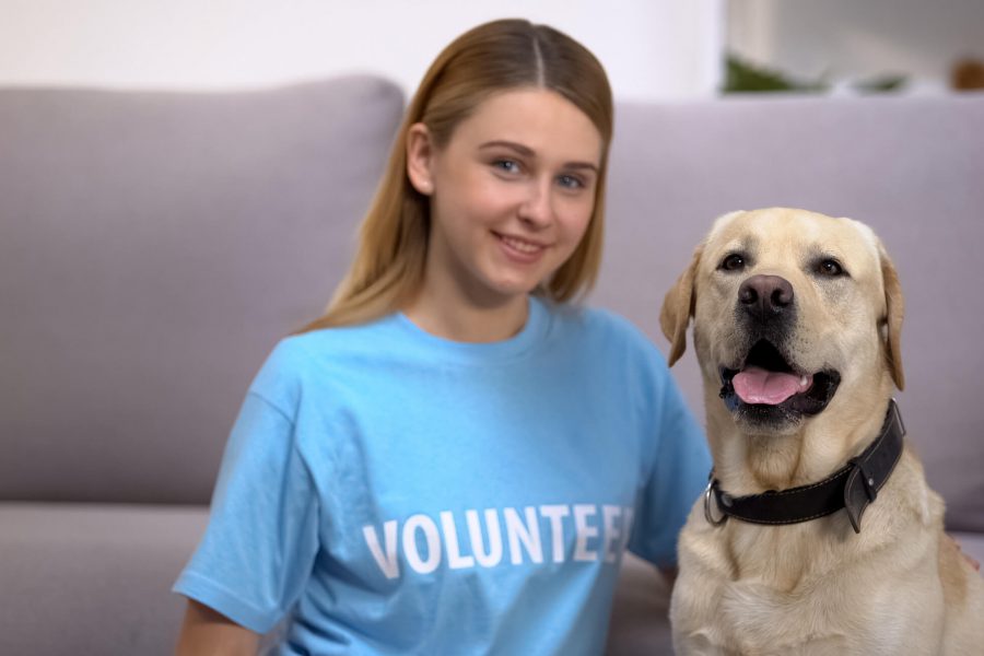 Teenage girl who is a volunteer sits next to a golden retriever