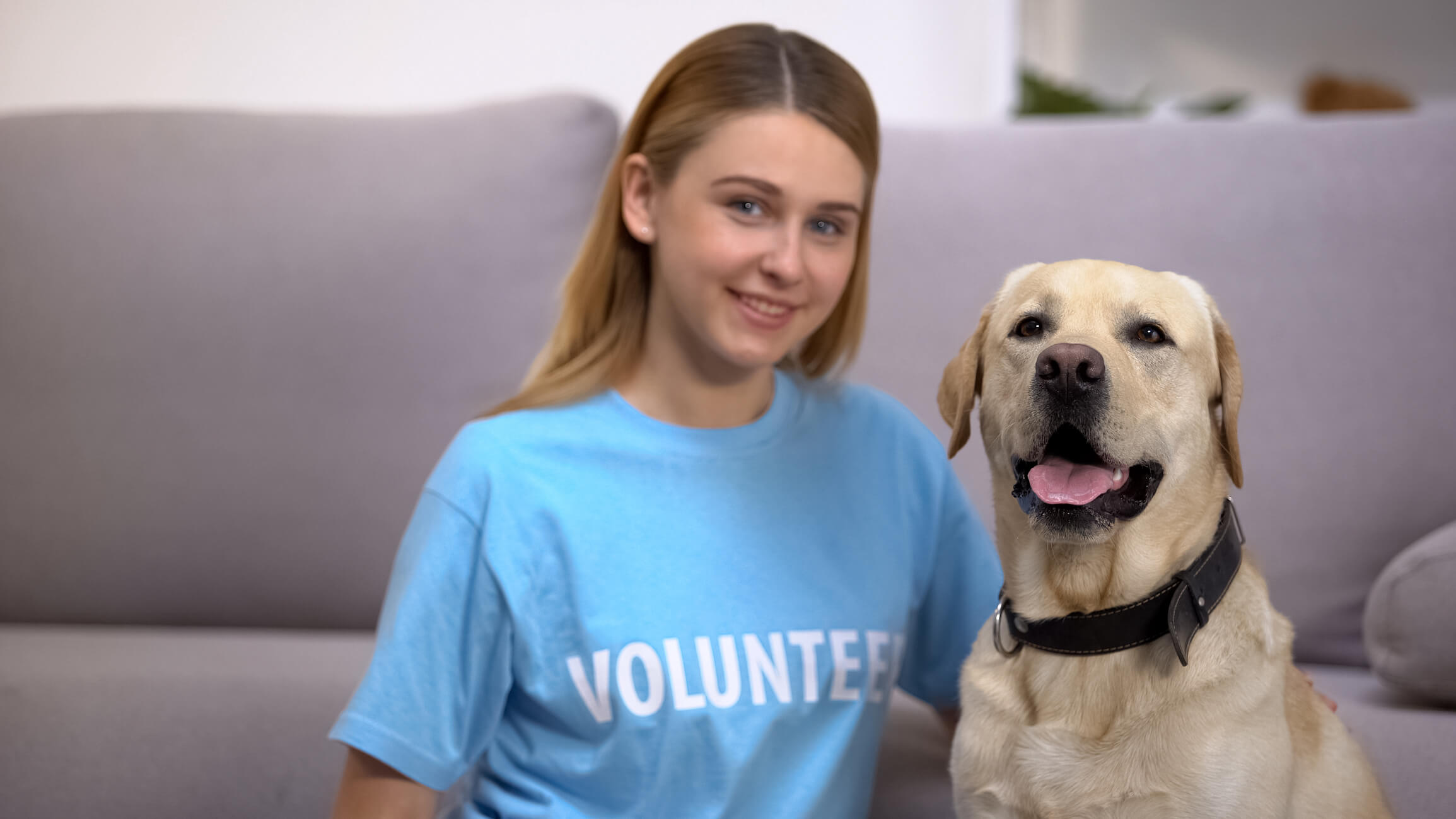 Teenage girl who is a volunteer sits next to a golden retriever